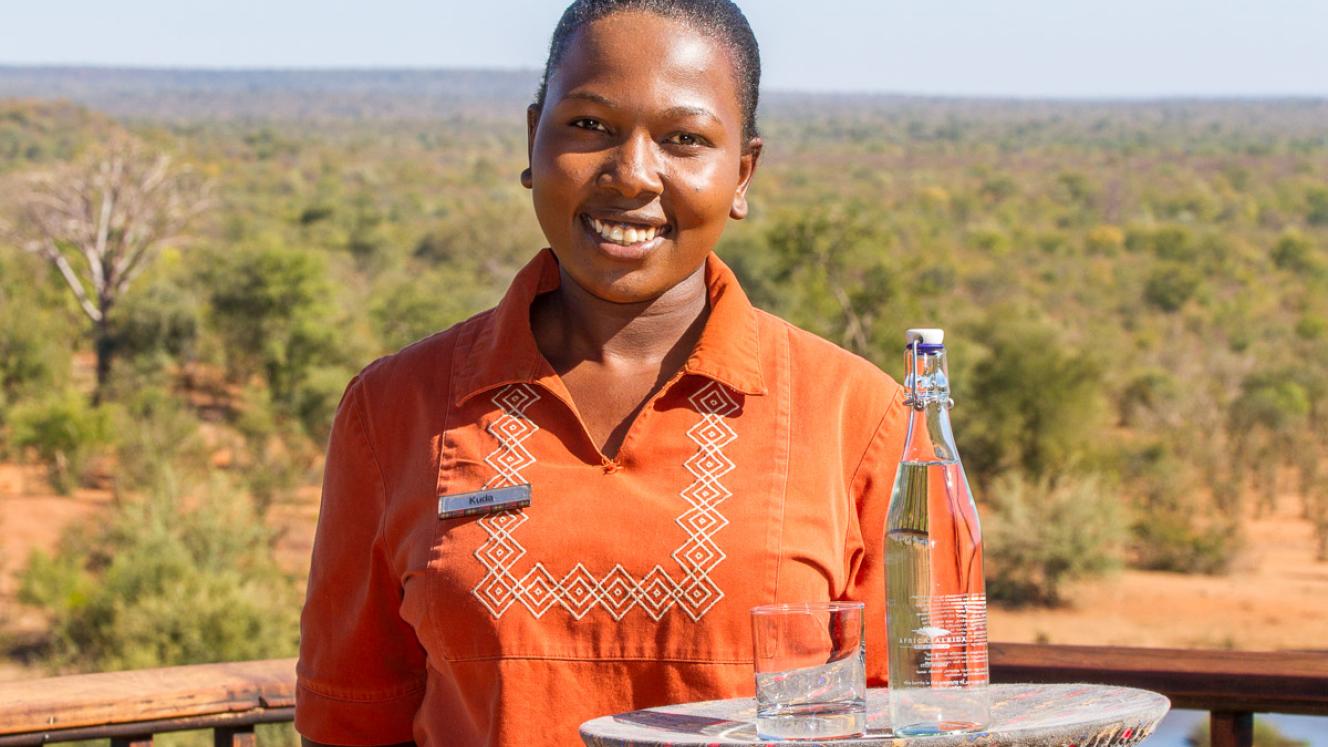 Waitress Kudakwashe Ruwuya serves water in one of the re-usable glass bottles.
